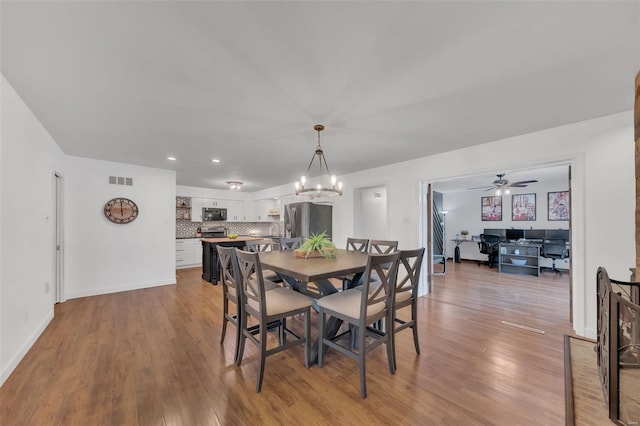 dining room with visible vents, light wood-style flooring, baseboards, and ceiling fan with notable chandelier
