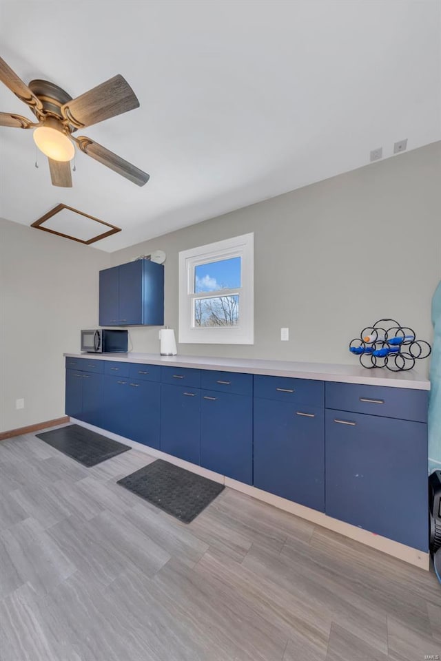 kitchen with light countertops, black microwave, blue cabinets, and baseboards