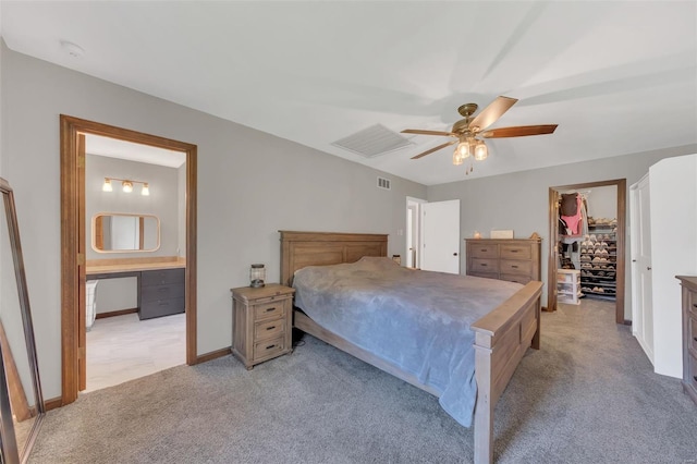 bedroom featuring a closet, light carpet, a spacious closet, ensuite bathroom, and ceiling fan