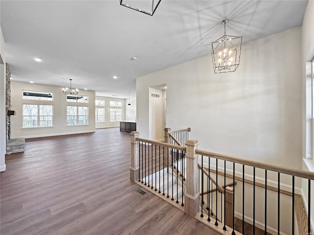 corridor featuring an inviting chandelier, recessed lighting, wood finished floors, an upstairs landing, and baseboards