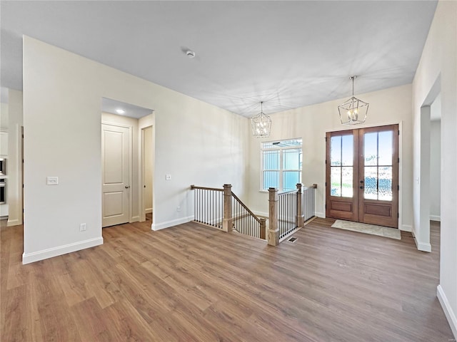 foyer entrance featuring a chandelier, french doors, baseboards, and wood finished floors