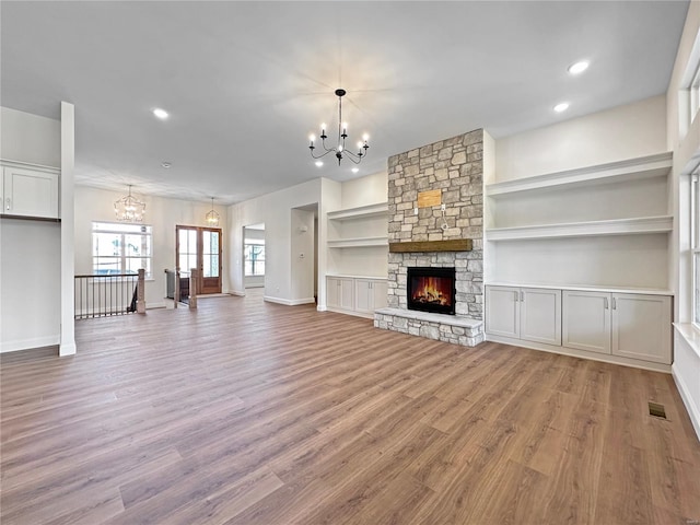 unfurnished living room with light wood-type flooring, a notable chandelier, and visible vents