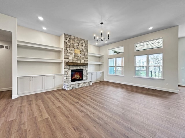 unfurnished living room with a notable chandelier, visible vents, baseboards, and wood finished floors