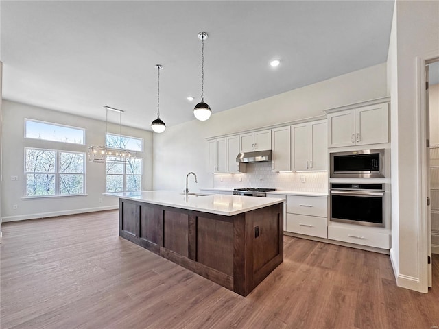 kitchen featuring tasteful backsplash, recessed lighting, light countertops, stainless steel appliances, and wood finished floors