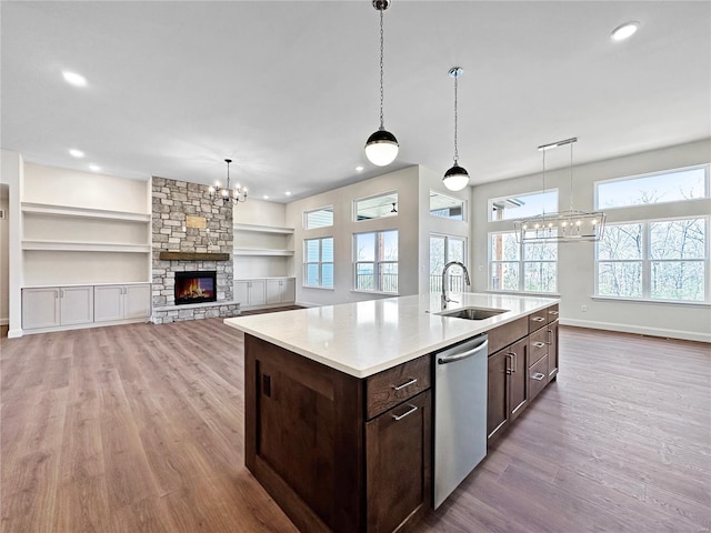 kitchen featuring light wood-style flooring, dark brown cabinets, dishwasher, a sink, and a notable chandelier
