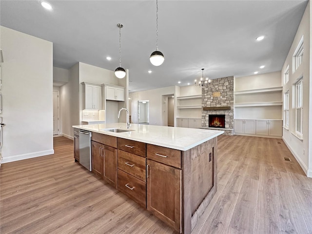 kitchen with a sink, stainless steel dishwasher, baseboards, and light wood-style flooring