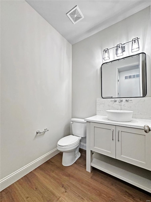 bathroom featuring toilet, wood finished floors, baseboards, and visible vents