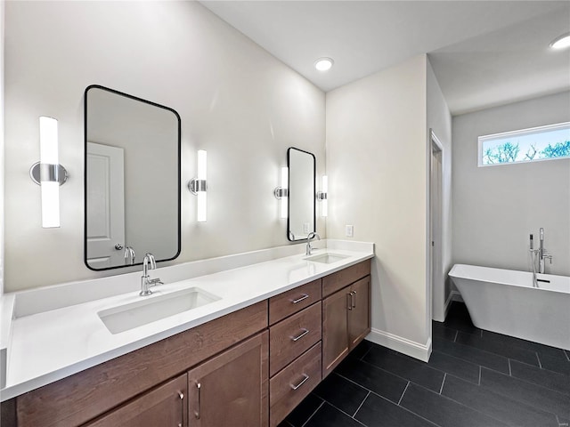 bathroom featuring double vanity, a sink, tile patterned flooring, and baseboards