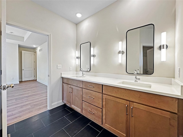 bathroom featuring visible vents, a sink, tile patterned floors, double vanity, and baseboards