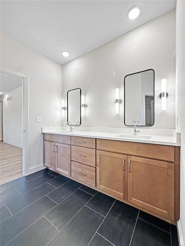 bathroom featuring tile patterned floors, double vanity, a sink, and baseboards