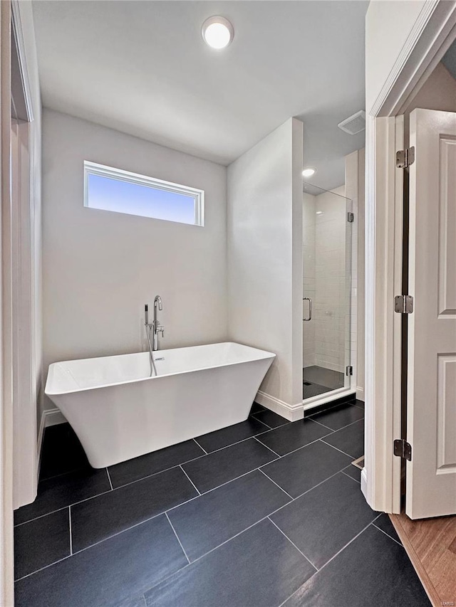 full bath featuring a stall shower, a freestanding tub, and tile patterned floors
