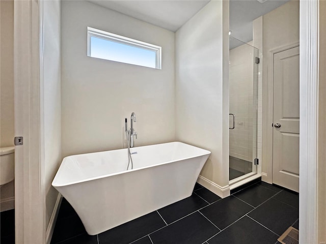 bathroom with baseboards, a freestanding bath, toilet, tile patterned flooring, and a stall shower
