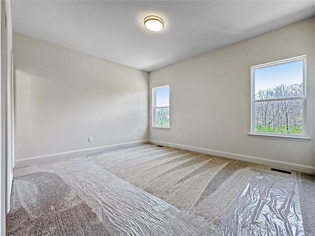 unfurnished room featuring carpet, visible vents, and baseboards