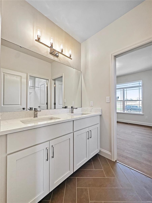 bathroom with a sink, baseboards, double vanity, and tile patterned flooring