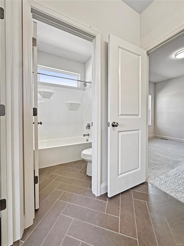 bathroom featuring tile patterned floors, toilet, and shower / washtub combination
