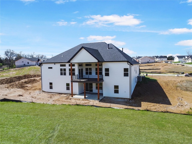 back of property with a patio area, a shingled roof, central air condition unit, and a lawn