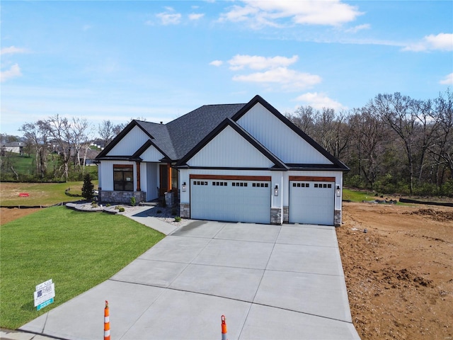 view of front of house with a garage, a front yard, stone siding, a shingled roof, and concrete driveway