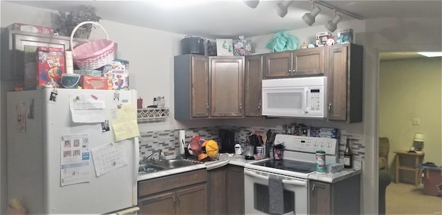 kitchen with white appliances, light countertops, a sink, and decorative backsplash