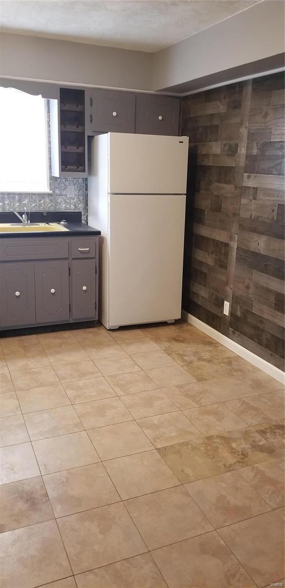 kitchen featuring dark countertops, freestanding refrigerator, and gray cabinets