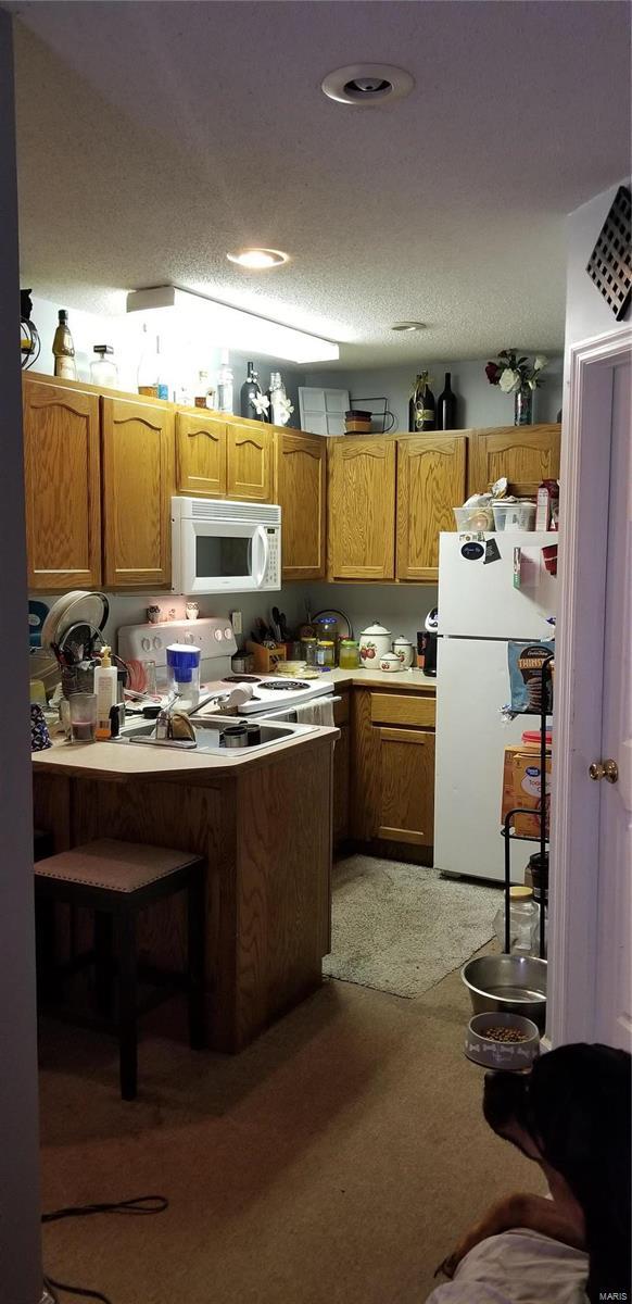 kitchen with light countertops, brown cabinetry, and white appliances