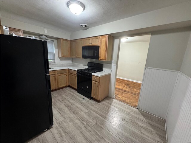 kitchen with visible vents, black appliances, a wainscoted wall, light countertops, and light wood finished floors