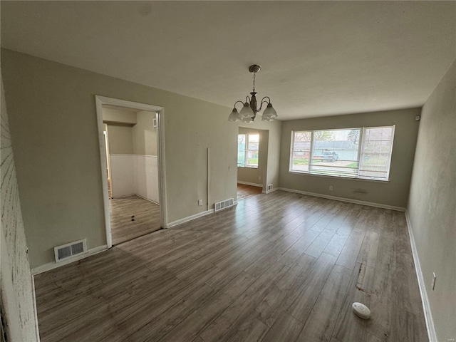 unfurnished dining area with visible vents, baseboards, a chandelier, and dark wood finished floors