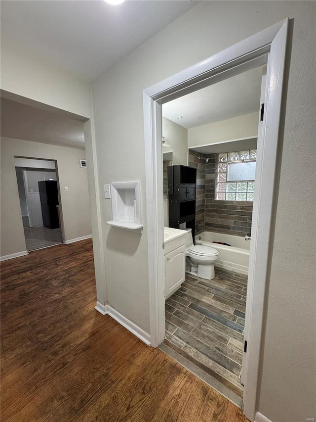 full bathroom with tub / shower combination, vanity, toilet, wood finished floors, and baseboards
