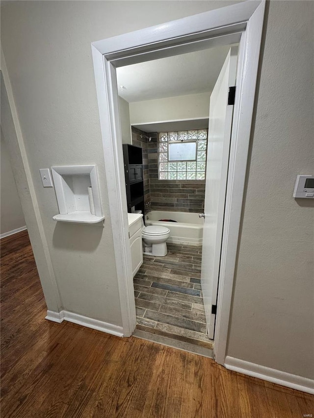 bathroom featuring vanity, baseboards, toilet, bathtub / shower combination, and wood finished floors
