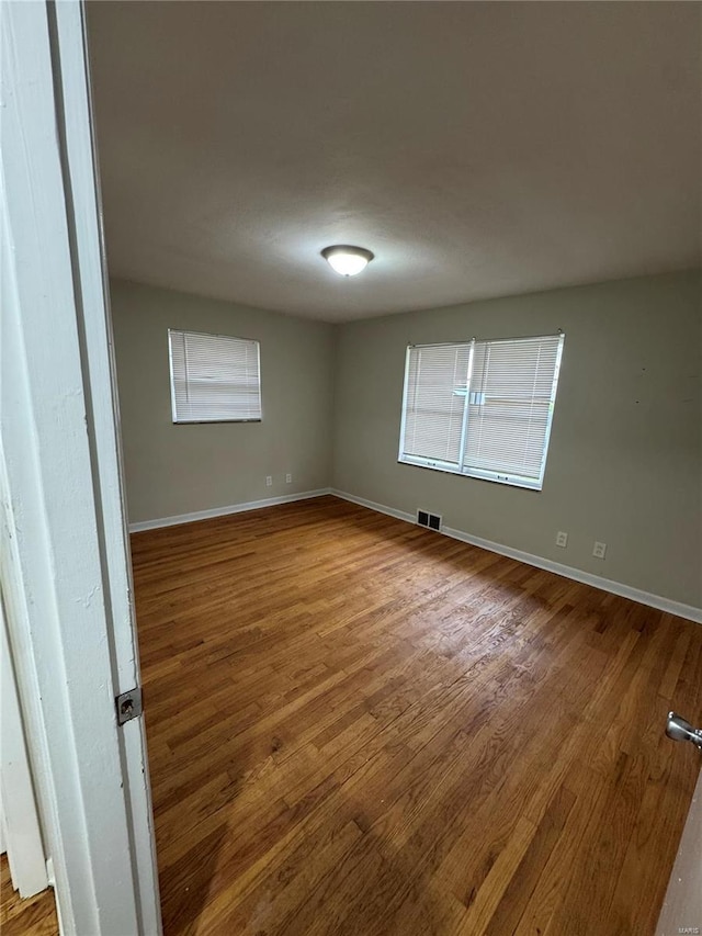 empty room with visible vents, baseboards, and wood finished floors