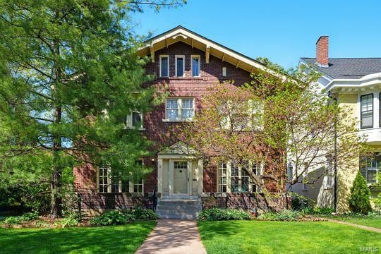 view of front facade featuring a front lawn, a chimney, and brick siding