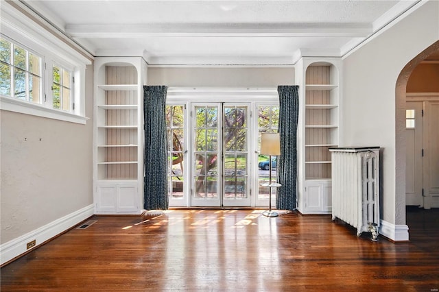 interior space with beamed ceiling, arched walkways, crown molding, and wood finished floors