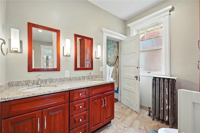 full bath featuring a sink, double vanity, and radiator