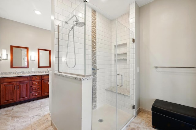 bathroom with baseboards, a sink, double vanity, and a stall shower