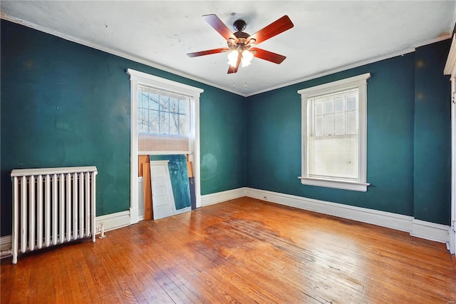 unfurnished living room featuring radiator, crown molding, baseboards, hardwood / wood-style flooring, and ceiling fan