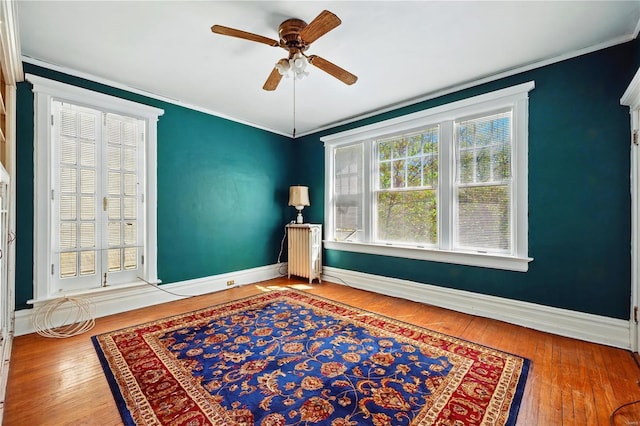 empty room featuring baseboards, ornamental molding, hardwood / wood-style flooring, and ceiling fan