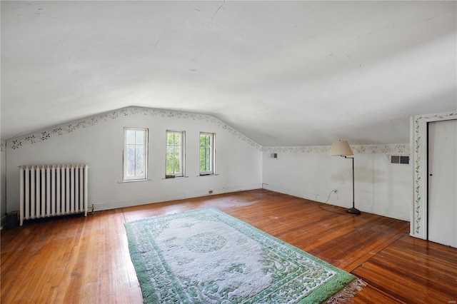 bonus room with radiator heating unit, hardwood / wood-style floors, lofted ceiling, and visible vents
