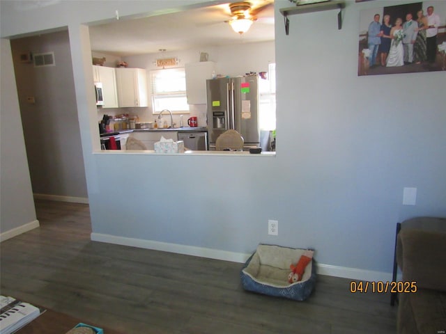 kitchen with a ceiling fan, visible vents, dark wood-style flooring, a sink, and stainless steel appliances