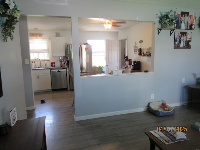kitchen featuring ceiling fan, white cabinets, wood finished floors, stainless steel appliances, and baseboards