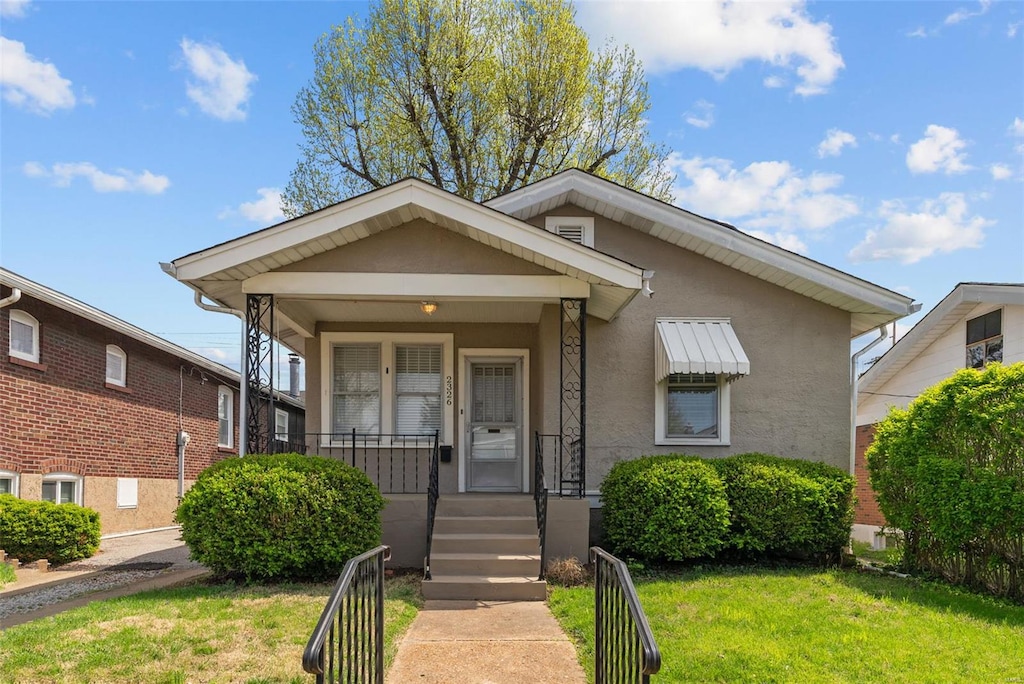 view of front of home featuring fence, a front lawn, covered porch, and stucco siding