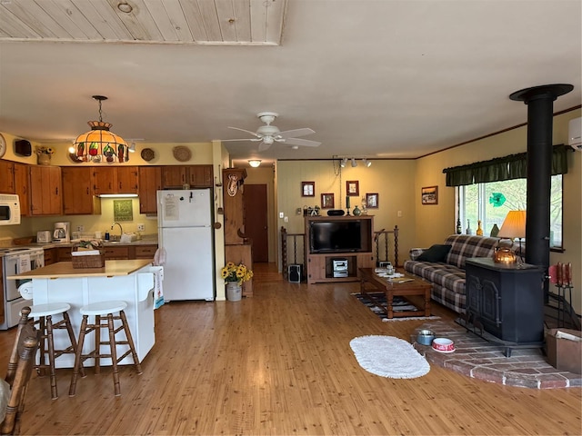 living room with a wood stove, a ceiling fan, wood finished floors, and rail lighting