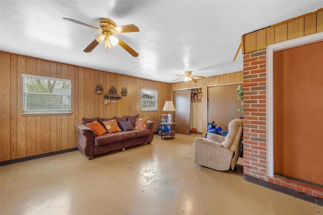 living room with ceiling fan, wooden walls, and finished concrete flooring