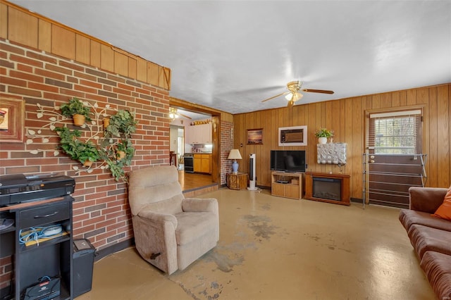 living room with ceiling fan, finished concrete floors, and wooden walls