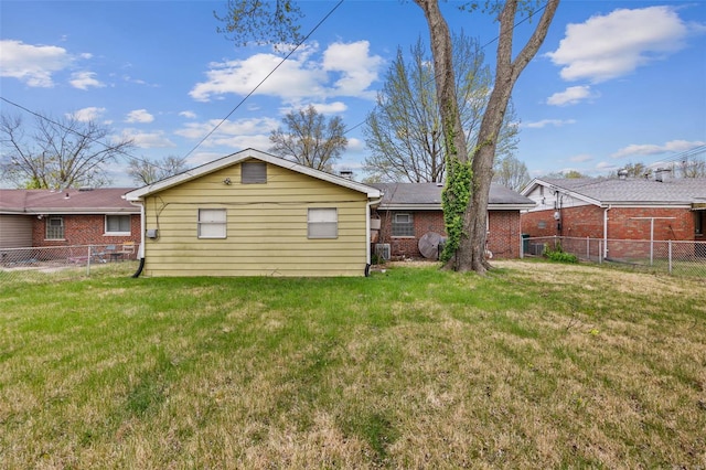 back of house with a fenced backyard, brick siding, and a yard