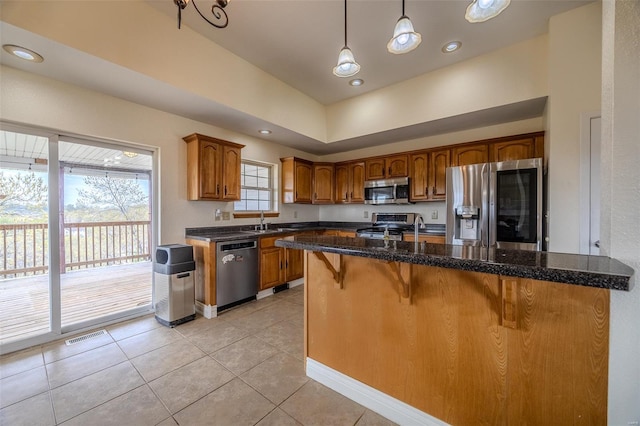 kitchen with brown cabinets, appliances with stainless steel finishes, light tile patterned flooring, and a breakfast bar