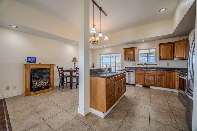 kitchen featuring brown cabinetry, a glass covered fireplace, a sink, and appliances with stainless steel finishes