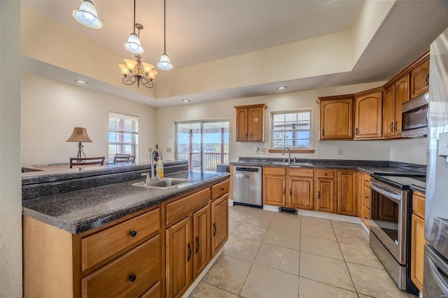 kitchen with a tray ceiling, brown cabinets, stainless steel appliances, and a sink