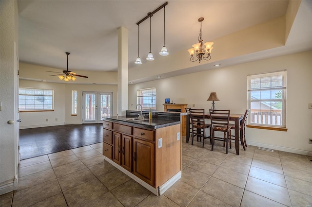 kitchen with brown cabinets, tile patterned floors, visible vents, a sink, and open floor plan