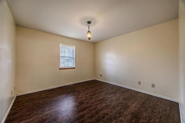 unfurnished room with baseboards, visible vents, and dark wood-style floors
