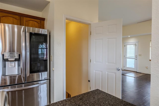 kitchen with dark stone counters, baseboards, wood finished floors, brown cabinets, and stainless steel fridge with ice dispenser