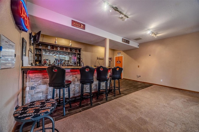 bar with track lighting, visible vents, a dry bar, carpet floors, and baseboards